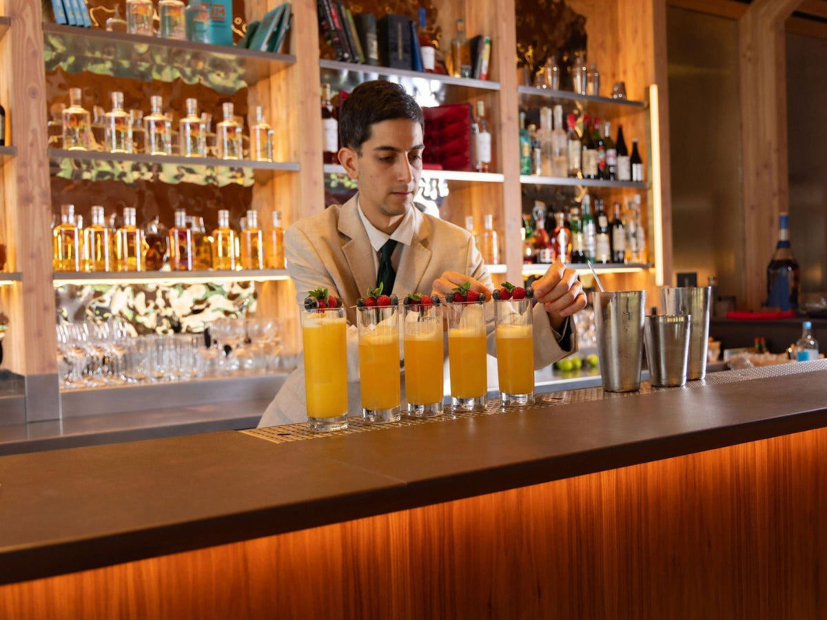 Rising Stars finalist garnishes a row of yellow cocktails with berries