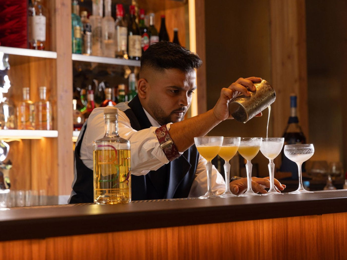 Rising Stars finalist pours cocktails into coupe glasses beside a Rum Bum bottle