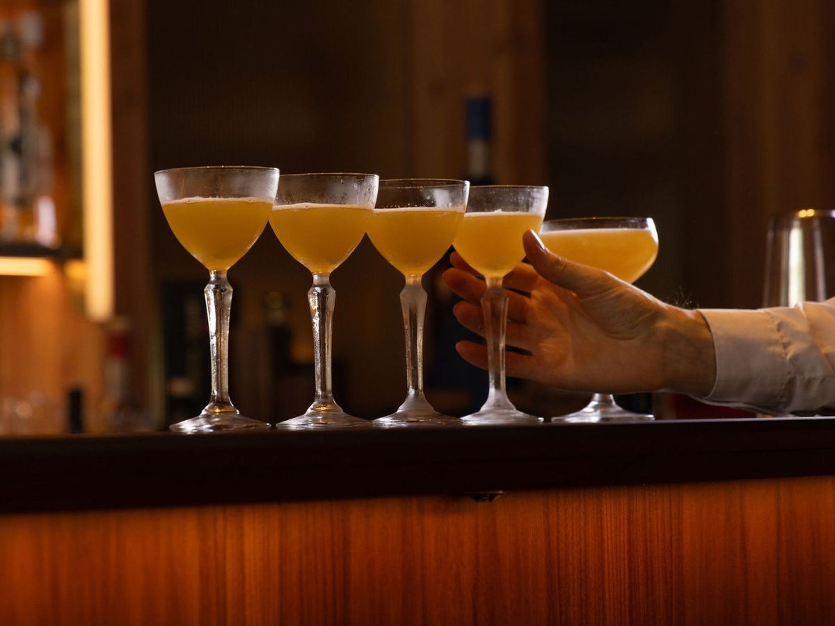 Five yellow cocktails lined up in coupe glasses at The Braywood