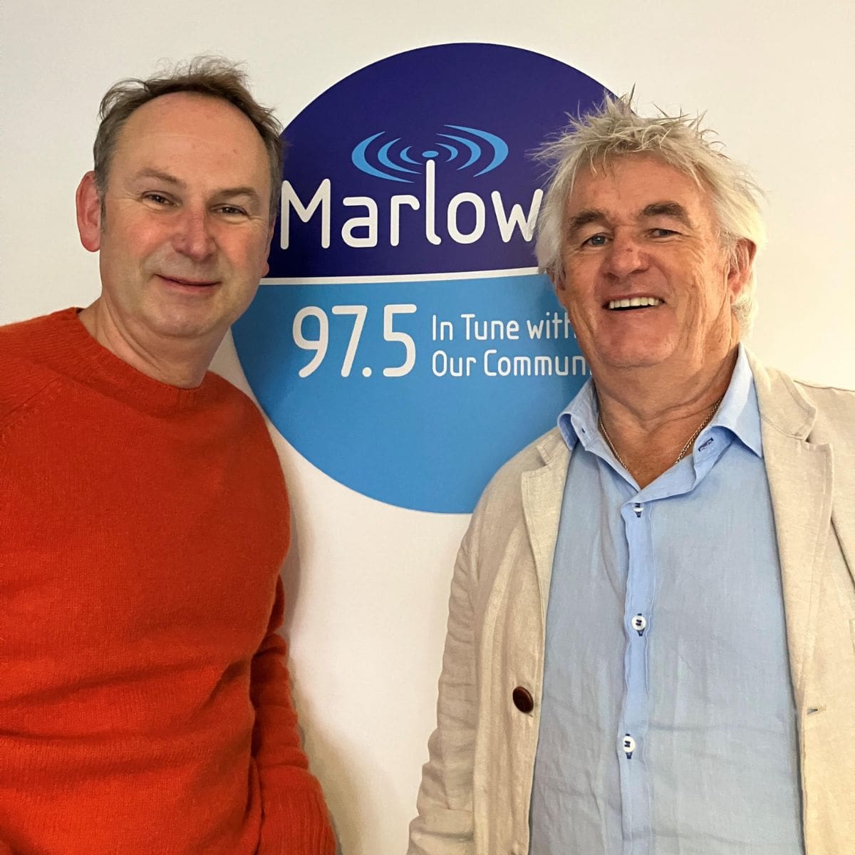 The original rum bum kevin Snook And James Winter standing in front of a Marlow FM 97.5 sign, smiling, during a radio interview related to craft rum.
