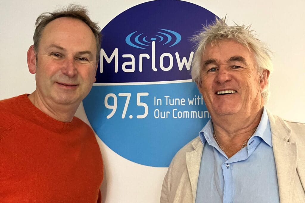 kevin snook & James Winter standing in front of a Marlow FM 97.5 sign, smiling, during what appears to be a radio interview or community feature related to craft rum.