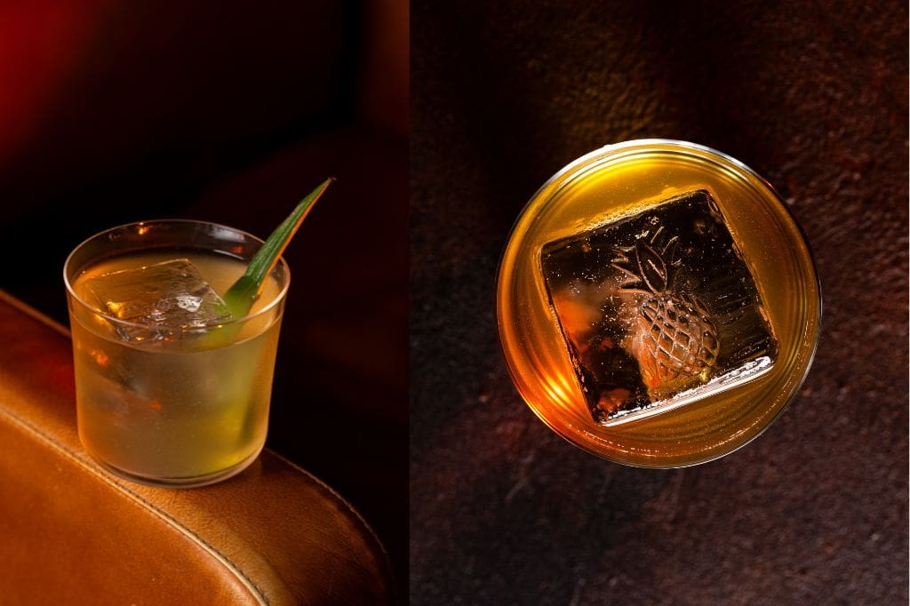 Two rum cocktails with large ice cubes, one embossed with a pineapple design.